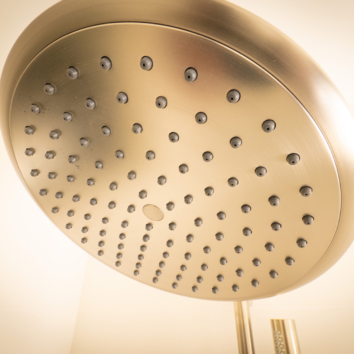 Brushed brass rain shower head in a high-end bathroom remodel