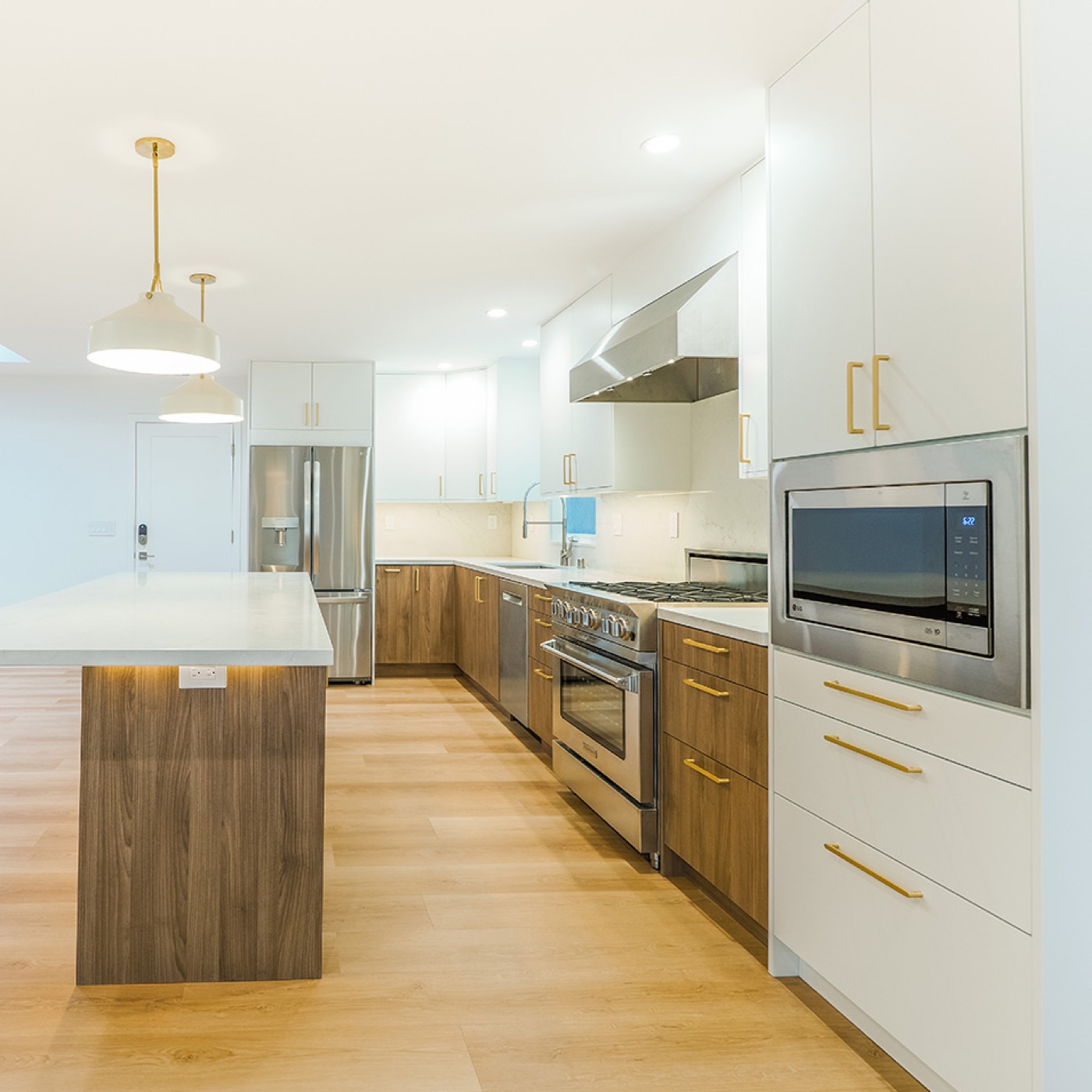 Remodeled kitchen with brass pendant lighting and professional range