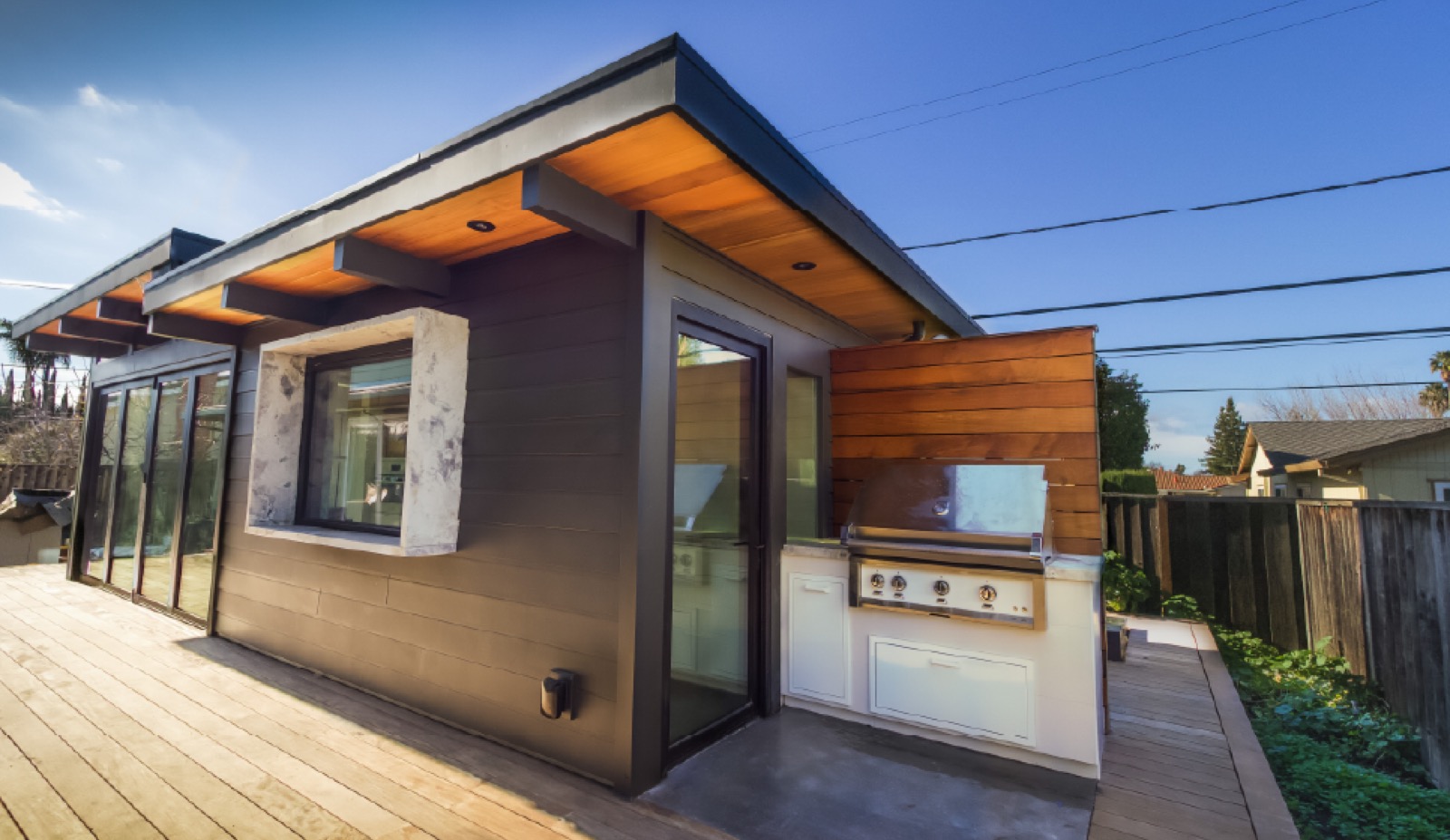 Modern backyard ADU with wood-clad eaves and outdoor kitchen built in the Bay Area